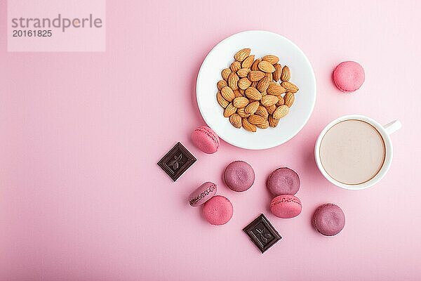 Lila und rosa Macaron oder Makronen Kuchen mit Tasse Kaffee und Mandeln auf Pastell rosa Hintergrund. Morninig  Frühling  Mode Zusammensetzung. Flachlage  Draufsicht  Kopierraum