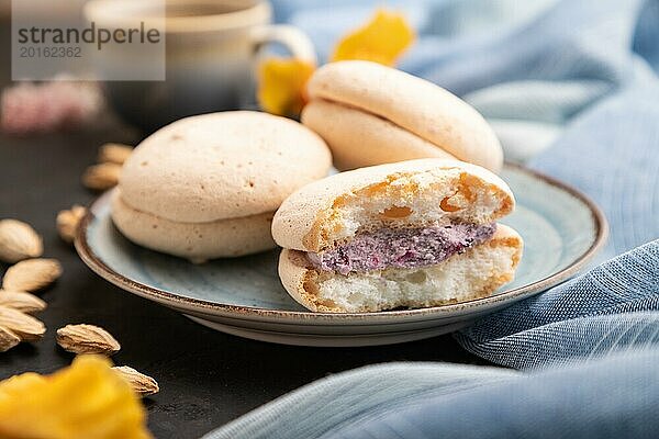 Meringues Kuchen mit einer Tasse Kaffee auf einem schwarzen Betonhintergrund und blauem Leinentuch. Seitenansicht  Nahaufnahme  selektiver Fokus