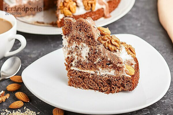 Hausgemachter Kuchen mit Milchcreme  Kakao  Mandel  Haselnuss auf einem schwarzen Betonhintergrund und einer Tasse Kaffee. Seitenansicht  Nahaufnahme  selektiver Fokus