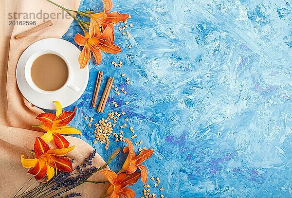 Orange Taglilie und Lavendelblüten und eine Tasse Kaffee auf einem blauen Betonhintergrund  mit orangefarbenem Textil. Morninig  Frühling  Mode Zusammensetzung. Flachlage  Draufsicht  Kopierraum