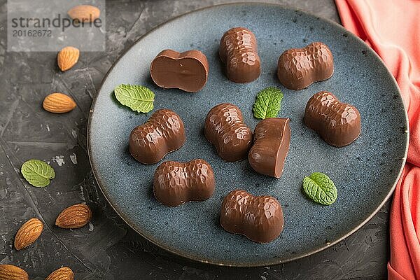 Schokoladenbonbons mit Mandeln auf einem schwarzen Betonhintergrund und rotem Textil. Seitenansicht  Nahaufnahme  selektiver Fokus