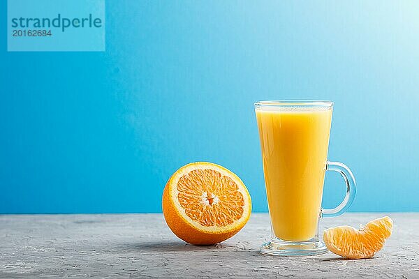 Glas Orangensaft auf einem grauen und blauen Hintergrund. Morninig  Frühling  gesundes Getränk Konzept. Seitenansicht  Kopie Raum