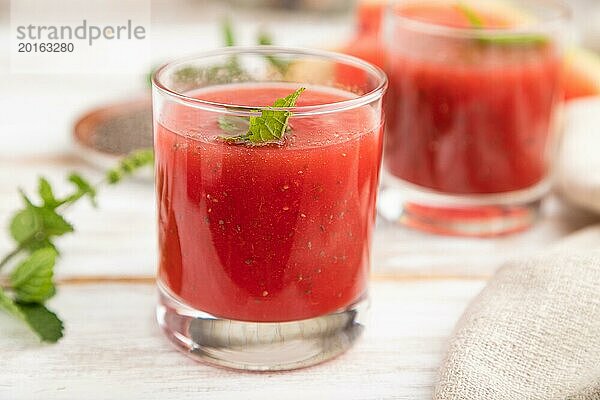 Wassermelonensaft mit Chiasamen und Minze in einem Glas auf einem weißen Holzhintergrund mit Leinenstoff. Gesundes Getränk Konzept. Seitenansicht  Nahaufnahme  selektiver Fokus