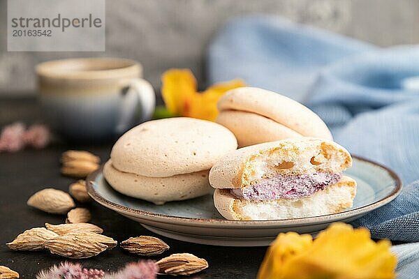 Meringues Kuchen mit einer Tasse Kaffee auf einem schwarzen Betonhintergrund und blauem Leinentuch. Seitenansicht  Nahaufnahme  selektiver Fokus