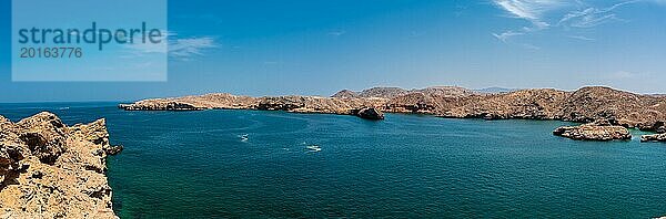 Panoramablick auf einen ruhigen Ozean mit felsiger Küstenlinie und klarem blauem Himmel  Oman  Asien