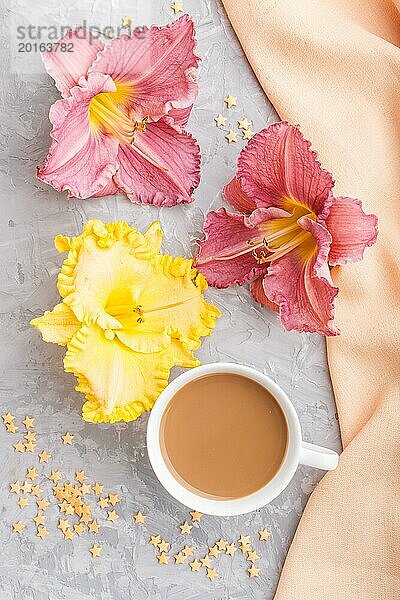 Gelbe und lila Taglilien Tasse Kaffee auf einem grauen Hintergrund Beton  mit orangefarbenen Textil. Morninig  Frühling  Mode Zusammensetzung. Flachlage  Draufsicht  Nahaufnahme