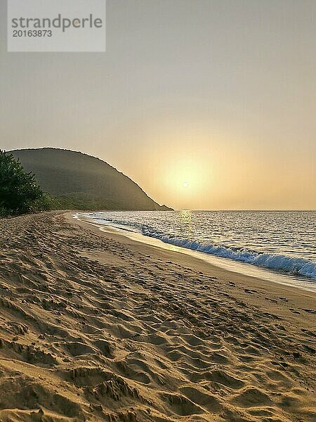 Blick über einen Strand  die Küste und das Meer im Sonnenuntergang. Im Vordergrund der leere Sandstrand von Grande Anse  Basse Terre  Guadeloupe  Französische Antillen  Karibik  Nordamerika