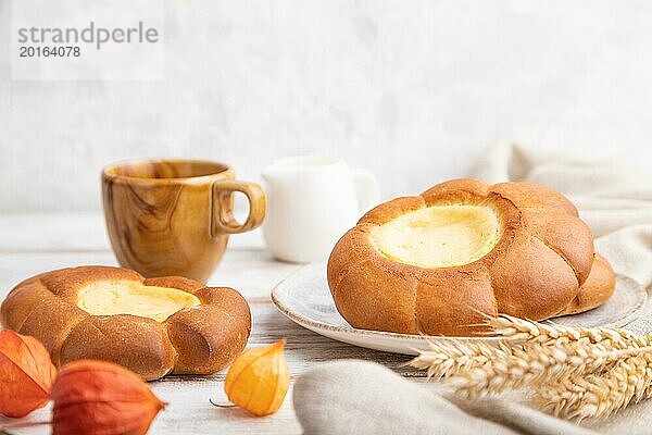 Saures Sahnebrötchen mit Tasse Kaffee auf weißem Holz und Betonhintergrund und Leinenstoff. Seitenansicht  Nahaufnahme  selektiver Fokus