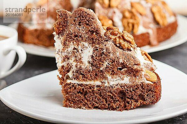 Hausgemachter Kuchen mit Milchcreme  Kakao  Mandel  Haselnuss auf einem schwarzen Betonhintergrund und einer Tasse Kaffee. Seitenansicht  Nahaufnahme  selektiver Fokus