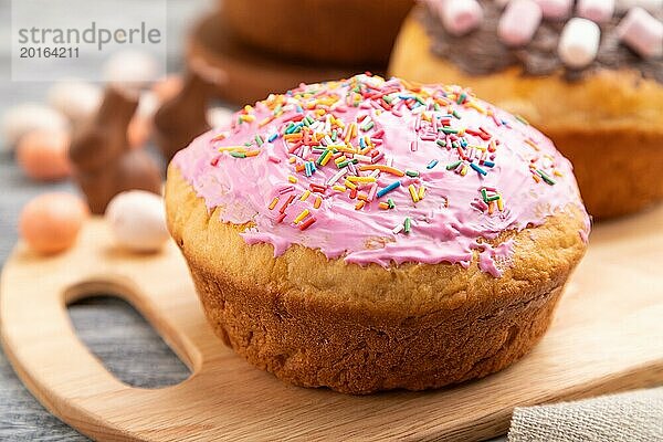 Hausgemachte glasierte und dekorierte Osterkuchen mit Schokoladeneiern und Kaninchen auf grauem Holzhintergrund und Leinentextil. Seitenansicht  selektiver Fokus  Nahaufnahme