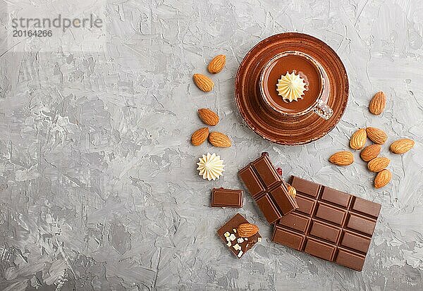 Tasse heiße Schokolade und Stücke von Milchschokolade mit Mandeln auf einem grauen Hintergrund aus Beton. Flachlage  Draufsicht  Kopierbereich
