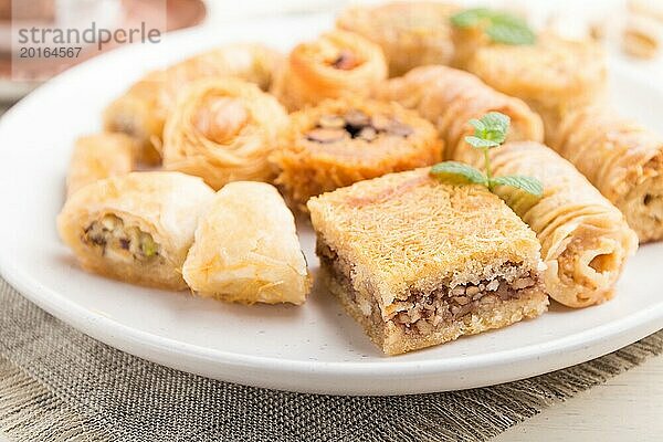 Traditionelle arabische Süßigkeiten (kunafa  baklava) und eine Tasse Kaffee auf einem weißen hölzernen Hintergrund und Leinenstoff. Seitenansicht  Nahaufnahme  selektiver Fokus