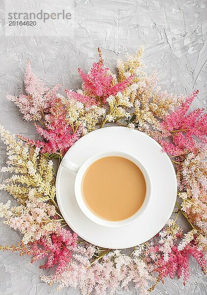 Rosa und rote Astilbe Blumen und eine Tasse Kaffee auf einem grauen Beton Hintergrund. Morninig  Frühling  Mode Zusammensetzung. Flachlage  Draufsicht  Kopierraum