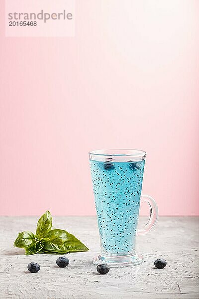 Glas Heidelbeere blau gefärbtes Getränk mit Basilikum Samen auf einem grauen und rosa Hintergrund. Morninig  Frühling  gesundes Getränk Konzept. Seitenansicht  Kopie Raum