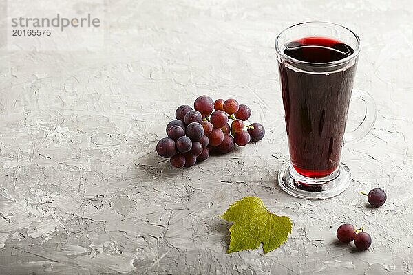 Glas roter Traubensaft auf einem grauen Hintergrund aus Beton. Morninig  Frühling  gesundes Getränk Konzept. Seitenansicht  Kopie Raum