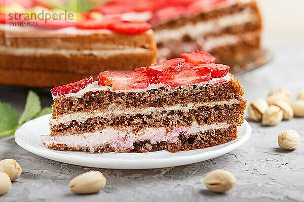 Hausgemachter Kuchen mit Joghurtcreme  Erdbeeren  Pistazien und einer Tasse Kaffee auf einem grauen Betonhintergrund. Seitenansicht  selektiver Fokus  Nahaufnahme