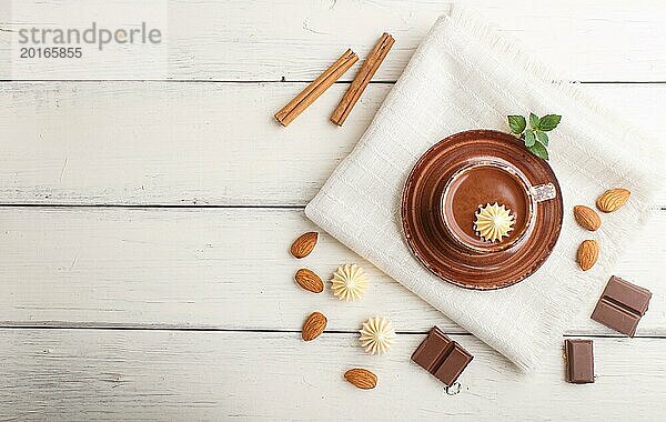Tasse heiße Schokolade und Milchschokoladenstückchen mit Mandeln auf weißem Holzhintergrund mit Leinenserviette. Draufsicht  flat lay  copy space
