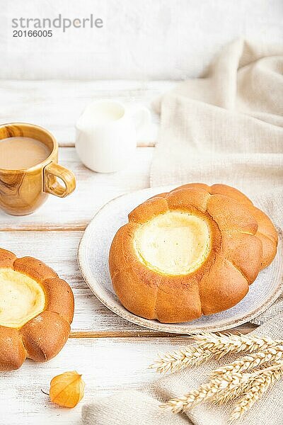 Saures Sahnebrötchen mit Tasse Kaffee auf weißem Holzhintergrund und Leinenstoff. Seitenansicht  Nahaufnahme  selektiver Fokus