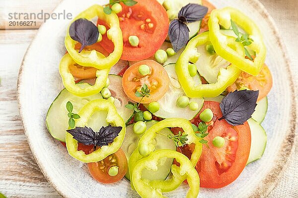 Vegetarischer Salat aus grünen Erbsen  Tomaten  Paprika und Basilikum auf weißem Holzhintergrund und Leinentextil. Draufsicht  Nahaufnahme  Flat Lay  selektiver Fokus