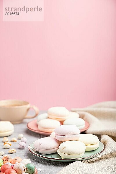 Bunte Zephir oder Marshmallow mit Tasse Kaffee und Dragees auf einem grauen und rosa Hintergrund und Leinenstoff. Seitenansicht  Nahaufnahme  selektiver Fokus  Kopierraum