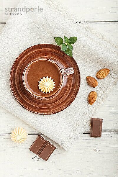 Tasse heiße Schokolade und Stücke von Milchschokolade mit Mandeln auf einem weißen hölzernen Hintergrund mit Leinenserviette. Draufsicht  Flachlegung  Nahaufnahme