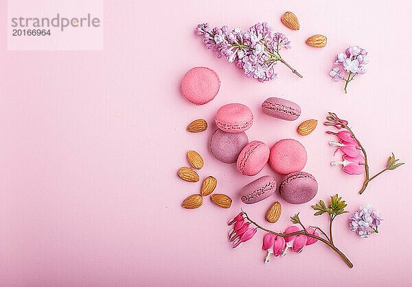 Lila und rosa Macaron oder Makronen Kuchen mit lila und blutenden Herzen Blumen auf Pastell rosa Hintergrund. Morninig  Frühling  Mode Zusammensetzung. Flachlage  Draufsicht  Kopierraum