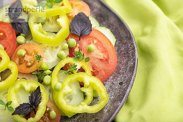 Vegetarischer Salat aus grünen Erbsen  Tomaten  Paprika und Basilikum auf einem grünen Textil. Draufsicht  Nahaufnahme  selektiver Fokus