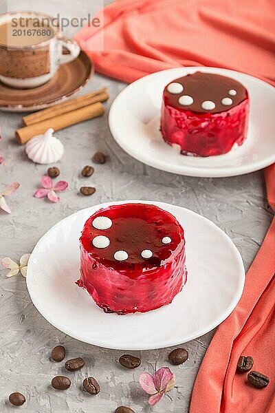 Roter Kuchen mit Soufflé Creme und einer Tasse Kaffee auf grauem Betonhintergrund und rotem Textil. Seitenansicht  Nahaufnahme  selektiver Fokus