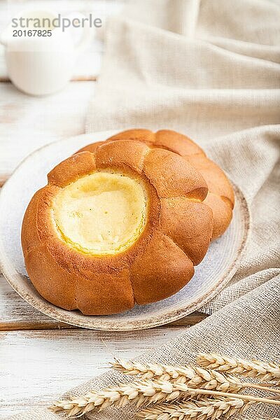 Saures Sahnebrötchen mit Tasse Kaffee auf weißem Holzhintergrund und Leinenstoff. Seitenansicht  Nahaufnahme  selektiver Fokus