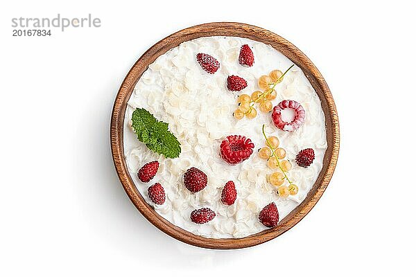 Reisflockenbrei mit Milch und Erdbeere in einer Holzschale vor weißem Hintergrund. Draufsicht  Flachlage  Nahaufnahme
