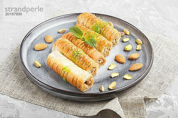 Baklava  traditionelle arabische Süßigkeiten in einem grauen Keramikteller auf einem grauen Betonhintergrund. Seitenansicht  Nahaufnahme