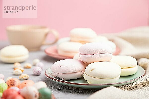 Farbige Zephir oder Marshmallow mit Tasse Kaffee und Dragees auf einem grauen und rosa Hintergrund und Leinenstoff. Seitenansicht  Nahaufnahme  selektiver Fokus