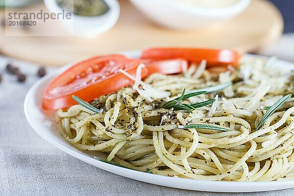 Spaghetti mit Pestosauce  Tomaten und Käse auf einer Leinentischdecke. Nahaufnahme  selektiver Fokus