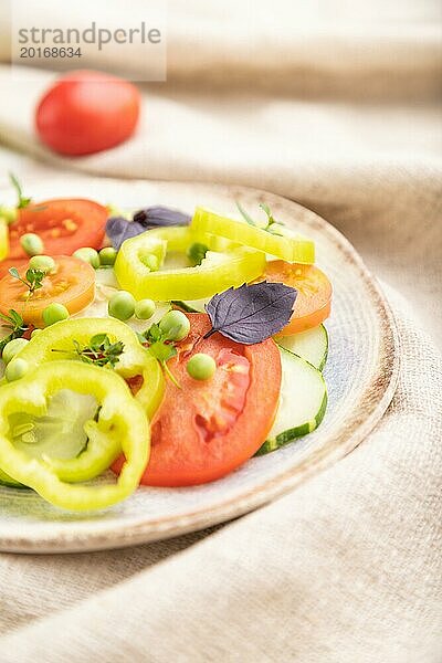 Vegetarischer Salat aus grünen Erbsen  Tomaten  Paprika und Basilikum auf weißem Holzhintergrund und Leinentuch. Seitenansicht  Nahaufnahme  selektiver Fokus