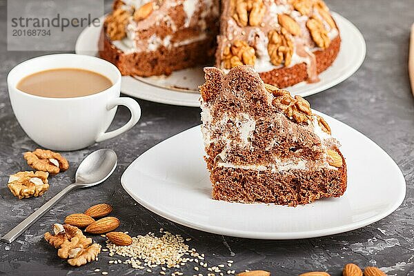 Hausgemachter Kuchen mit Milchcreme  Kakao  Mandel  Haselnuss auf einem schwarzen Betonhintergrund und einer Tasse Kaffee. Seitenansicht  Nahaufnahme  selektiver Fokus