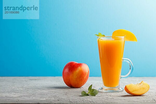 Glas Pfirsichsaft auf einem grauen und blauen Hintergrund. Morninig  Frühling  gesundes Getränk Konzept. Seitenansicht  Kopie Raum