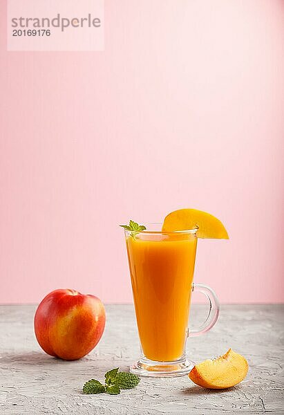 Glas Pfirsichsaft auf einem grauen und rosa Hintergrund. Morninig  Frühling  gesundes Getränk Konzept. Seitenansicht  Kopie Raum