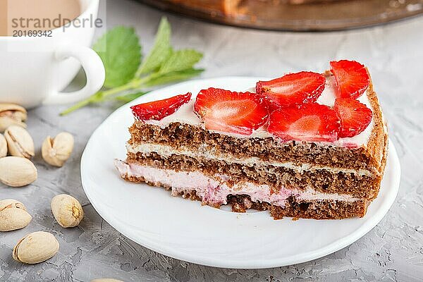 Hausgemachter Kuchen mit Joghurtcreme  Erdbeeren  Pistazien und einer Tasse Kaffee auf einem grauen Betonhintergrund. Seitenansicht  selektiver Fokus  Nahaufnahme