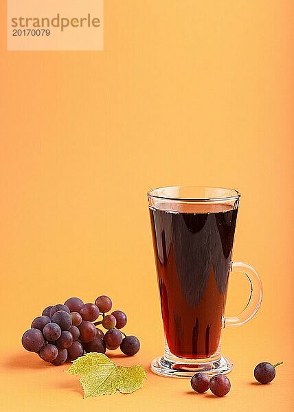 Glas mit rotem Traubensaft auf orangefarbenem Hintergrund. Morninig  Frühling  gesundes Getränk Konzept. Seitenansicht  Kopie Raum