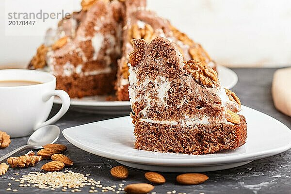 Hausgemachter Kuchen mit Milchcreme  Kakao  Mandel  Haselnuss auf einem schwarzen Betonhintergrund und einer Tasse Kaffee. Seitenansicht  Nahaufnahme  selektiver Fokus