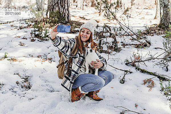 Lächelnder Wanderer macht Selfie mit Hund im Schnee