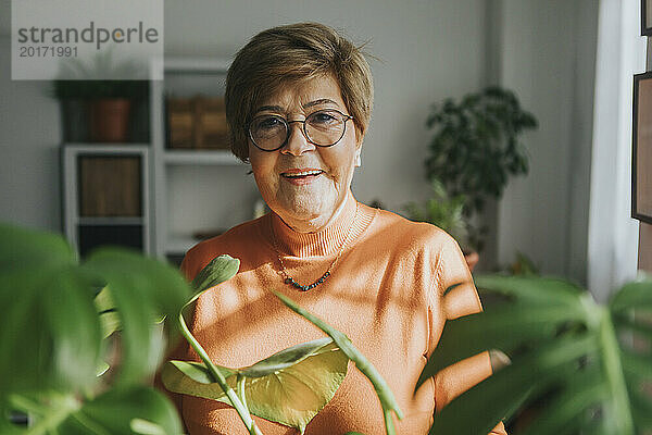 Lächelnde Frau in der Nähe von Pflanzen zu Hause