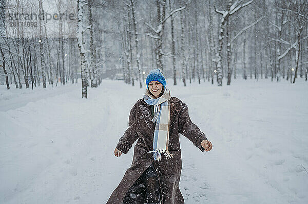 Glückliche reife Frau  die im Park im Schnee spaziert