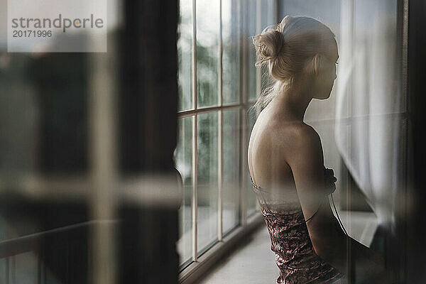 Pensive woman sitting on window sill at home