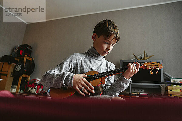 Junge spielt zu Hause Ukulele