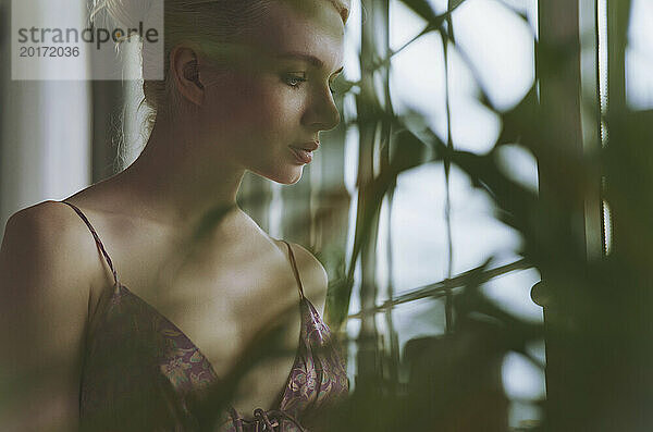 Young pensive woman looking out of window