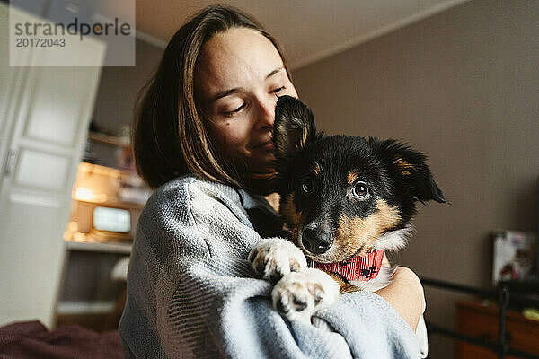 Frau hält zu Hause Hund im Arm