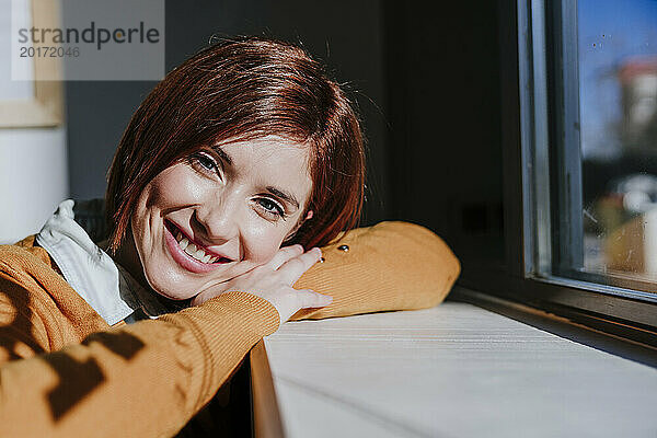 Smiling woman enjoying sunlight in cafe