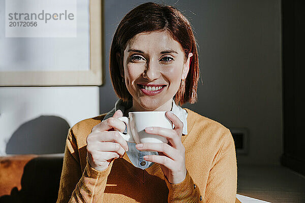 Lächelnde Frau hält Kaffeetasse im Café