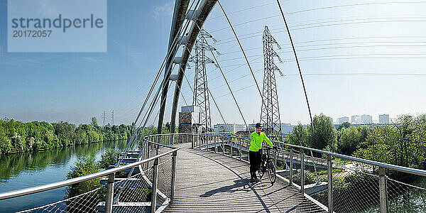 Älterer Mann läuft mit Fahrrad auf der Dessau-Modern-Brücke in Deutschland